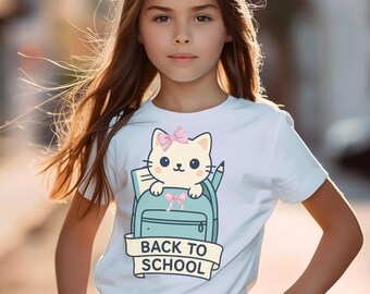 May include: White t-shirt featuring a cartoon cat with a pink bow, peeking out of a blue backpack. A banner below reads "BACK TO SCHOOL". The design includes a pencil and a pink bow on the backpack.