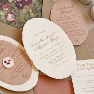 May include: Wedding invitation suite featuring a floral envelope liner, invitation cards, and RSVP cards. The main invitation is off-white with the names Priscilla Morris and Hernan Diaz. Additional cards include reception details and reply information.