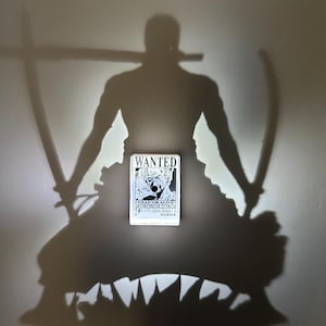 Puede incluir: Un cartel blanco de "SE BUSCA" con una ilustración en blanco y negro de un personaje con espadas. El cartel está centrado, con una sombra del personaje y espadas detrás. La sombra se proyecta sobre una superficie gris claro.