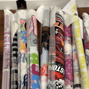 a collection of colorful, patterned rolls of paper or fabric, each with unique designs and text.