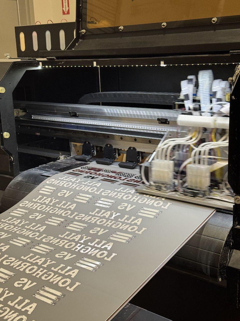 a large printer with a printed document or material resting on top of it. The printer appears to be in operation, as the document is visible on the surface.
