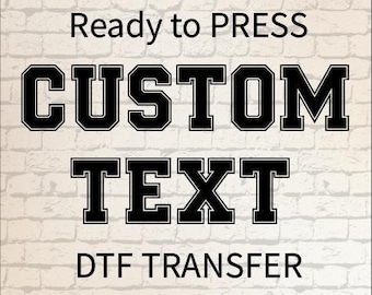 Puede incluir: Una hoja de transferencia DTF con el texto Ready to PRESS en una fuente sencilla, seguido de las palabras CUSTOM TEXT en una fuente negra grande y negrita de estilo universitario con borde blanco, y el texto DTF TRANSFER en negro abajo.