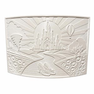 May include: A rectangular off-white wall plaque featuring a relief carving of a fantasy landscape. The scene depicts a central castle, a winding path leading to it, a pair of shoes in the foreground, a tornado on the left, and a hot air balloon.