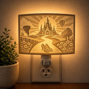 Pode incluir: Uma luz noturna retangular de tomada com uma cena quente e iluminada de um castelo, um caminho sinuoso, um tornado, um bal&atilde;o de ar quente e um par de sapatos. O design em tons de bege e creme emite um brilho suave e ambiente.