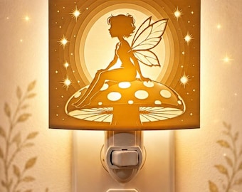 Könnte beinhalten: Ein quadratisches Steckdosen-Nachtlicht mit der warm leuchtenden Silhouette einer Fee mit Flügeln, die auf einem gepunkteten Pilz sitzt. Das Motiv wird von hinten beleuchtet, wirft ein sanftes goldenes Licht und ist vor einem kreisförmigen Hintergrund mit sternartigen Akzenten platziert.