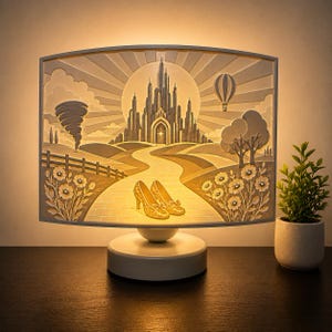 May include: A rectangular, illuminated table lamp featuring a layered paper-cut style scene of a castle, a winding path, a tornado, a hot air balloon, and a pair of glittery gold high-heeled shoes in the foreground, all set on a round base.