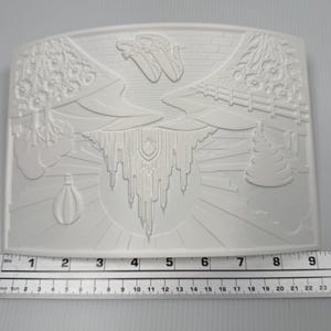 May include: A white rectangular silicone mold featuring an embossed landscape design with a hot air balloon, flowers, a fence, and a central castle-like structure. A ruler placed at the bottom shows the mold width is approximately 9.5 inches.