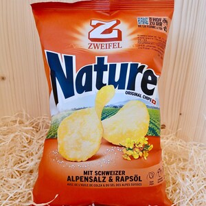 May include: A bag of Zweifel Nature Original Chips with Swiss Alpine Salt and Rapeseed Oil. The bag is orange and features a large blue "Nature" logo and a close-up of the chips.