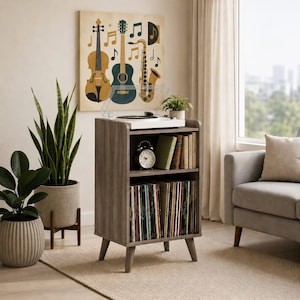 May include: A gray wooden record player stand with four tapered legs, featuring an open top shelf holding a white turntable, a middle shelf with an alarm clock and books, and a bottom shelf filled with vinyl records in a vertical arrangement.