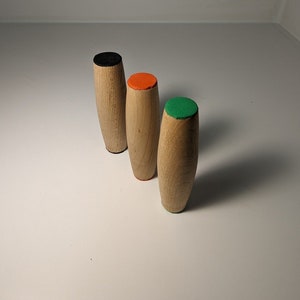 May include: Three wooden spinning tops with different colored tops. The tops are black, orange, and green.