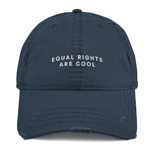 May include: A distressed navy blue baseball cap with the embroidered text "EQUAL RIGHTS ARE COOL" in white. The cap has a pre-curved bill and a worn, vintage look.