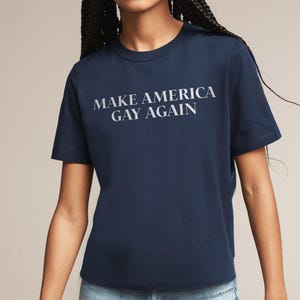 May include: A navy blue t-shirt with the text "Make America Gay Again" printed in white.