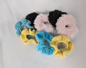 May include: A set of six colorful hair scrunchies. The scrunchies are made of soft, fuzzy fabric and come in a variety of colors, including pink, yellow, blue, and black.