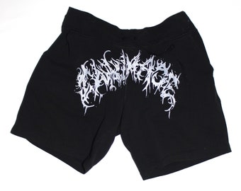 May include: Black shorts with a white, stylized graphic across the front. The shorts have a drawstring waistband and are made of a soft material. The graphic appears to be a decorative design.