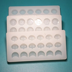 May include: Three white silicone molds for making resin crafts. The top mold has six round cavities. The middle mold has six round cavities with different designs. The bottom mold has 18 cavities with different shapes.