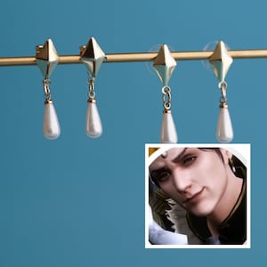 May include: Four gold earrings with a pointed top and a pearlescent drop. The earrings are hanging from a gold bar.