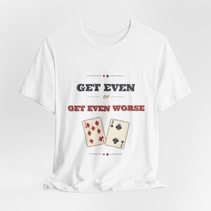 May include: A white short-sleeve t-shirt featuring the black text GET EVEN and red text GET EVEN WORSE. Below the text are two playing cards, a seven of diamonds and a two of clubs, with small card suit symbols above and below the graphic design.