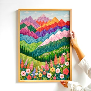 May include: A framed art print depicting a colourful mountain landscape and a wildflower meadow. The mountains are painted in shades of pink, purple, orange, and green. The artwork is presented in a light wooden frame.