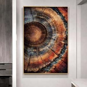 May include: A framed print showing a detailed cross-section of a tree stump. The artwork displays concentric rings in brown, orange, and black hues, set within a gold frame. The natural textures and colours create a rustic aesthetic.