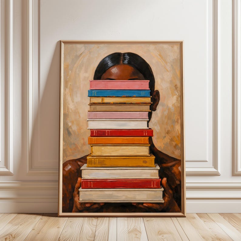 Puede incluir: Impresi&oacute;n art&iacute;stica enmarcada que representa a una persona sosteniendo una pila de libros coloridos frente a su rostro. Los libros son de varios colores, incluyendo rosa, azul y rojo. La obra de arte tiene un fondo c&aacute;lido y neutro y un marco de madera.