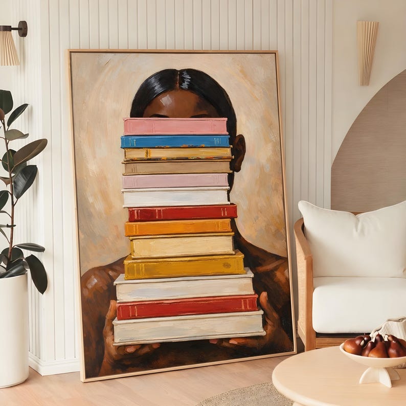 Puede incluir: Una pintura enmarcada representa a una persona con cabello y piel oscuros, sosteniendo una pila de libros coloridos frente a su rostro. Los libros tienen varios colores, incluyendo rosa, azul y amarillo. La obra de arte se exhibe en una habitaci&oacute;n bien iluminada.