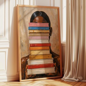 Puede incluir: Una impresi&oacute;n art&iacute;stica enmarcada que representa a una persona sosteniendo una pila de libros coloridos frente a su rostro. La obra de arte tiene una paleta de colores c&aacute;lidos y un marco dorado. Los libros son de varios colores, incluyendo rosa, azul y rojo.