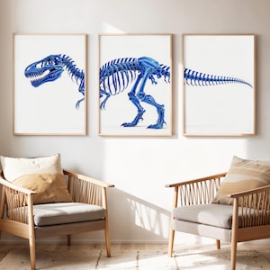 Puede incluir: Tres impresiones artísticas enmarcadas que muestran un esqueleto azul de Tyrannosaurus Rex sobre un fondo blanco. Las impresiones se exhiben en un salón con sillas de madera y cojines de tonos neutros. La obra de arte es una interpretación moderna de una ilustración científica.