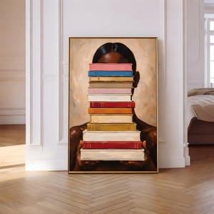 Puede incluir: Una impresi&oacute;n art&iacute;stica enmarcada que representa a una persona sosteniendo una pila de libros coloridos frente a su rostro. Los libros son de varios colores, incluyendo rojo, rosa, azul y amarillo. La obra de arte est&aacute; enmarcada en un marco dorado.