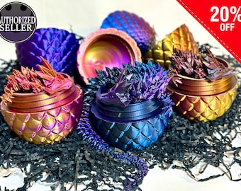 May include: Five dragon egg-shaped containers with iridescent finishes. Each container has a dragon figurine inside. The containers are arranged on a black shredded paper background. 20% OFF.