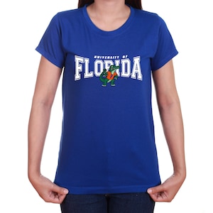 Peut inclure: T-shirt bleu royal avec un graphique blanc d'un alligator tenant un ballon de football et le texte "University of Florida".