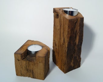 May include: Two wooden candle holders with a rustic finish. Each holder has a small, round, metal cup for a tea light candle.
