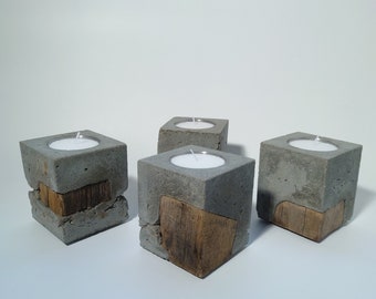 May include: Four gray concrete candle holders with a wood accent. Each holder has a small white candle inside.