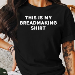 May include: Black t-shirt with white text that reads "This is my breadmaking shirt."