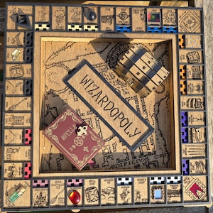 May include: A wooden Wizardopoly board game with a map of the game board, a small book, and a chest. The board is made of wood and has a black border. The game pieces are made of wood and have a variety of colours. The game is designed for 2-4 players.