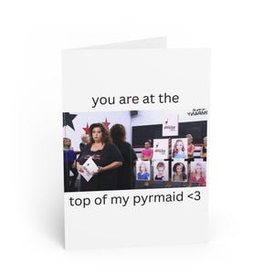 Op de afbeelding: Witte wenskaart met de tekst "you are at the top of my pyrmaid <3". De kaart toont een foto van een vrouw die een papier vasthoudt en een groep mensen op de achtergrond.