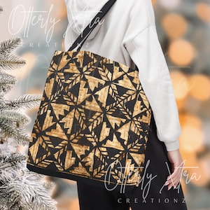 May include: Black tote bag with a geometric pattern in shades of brown and tan. The bag has a black strap and trim. The text "Otterly Xtra CREATIONZ" is visible on the bag. The bag is being held by a person.