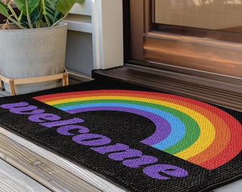 May include: A black welcome mat with a rainbow arch and the word "welcome" in purple lettering.