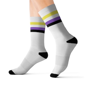 Peut inclure: Chaussettes blanches montantes avec un motif de rayures noires, violettes et jaunes. Les chaussettes sont faites d'un matériau doux et confortable et sont parfaites pour un usage quotidien.