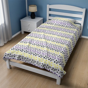 May include: A white twin-sized bed frame with a white and yellow patterned bedspread featuring a repeating design of black paw prints and cat faces. The bedspread is tucked in on all sides and the bed frame has a headboard and footboard.