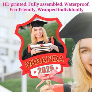 Może przedstawiać: Czerwono-biały rekwizyt do fotobudki na zakończenie szkoły z wycięciem na zdjęcie. Rekwizyt zawiera czapkę absolwenta, napis "MIRANDA 2025" i r&oacute;żową kokardkę.