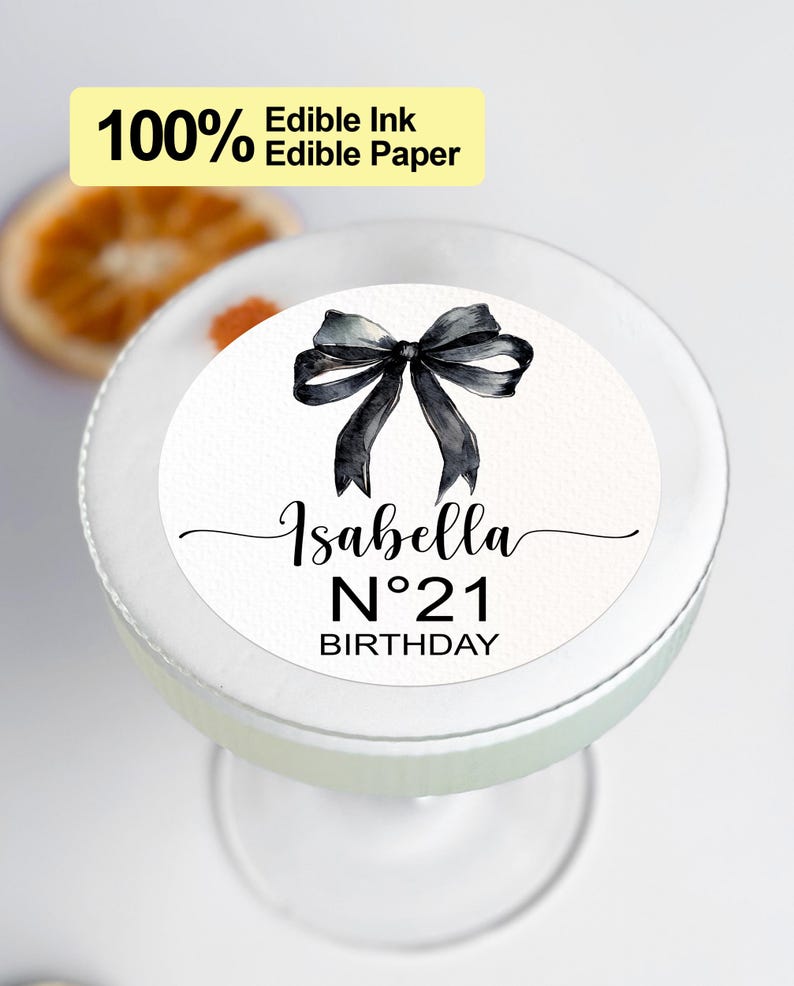 K&ouml;nnte beinhalten: Runder essbarer Kuchentopper in Wei&szlig; mit einer schwarzen Schleife und dem Text "Isabella N&deg;21 GEBURTSTAG".