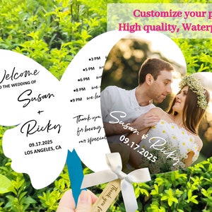 May include: White butterfly-shaped wedding fan with a photo of a couple in a heart-shaped frame. The fan has the text "Welcome to the wedding of Susan + Ricky 09.17.2025 Los Angeles, CA" and "Thank you for being our special" on the left side. The heart-shaped frame has the text "Susan & Ricky 09.17.2025" and a photo of a couple in a garden setting.