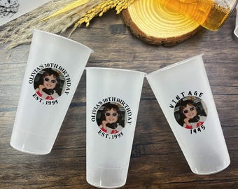Puede incluir: Tres vasos de plástico blanco con diseños personalizados de cumpleaños. Cada vaso presenta una imagen circular de una persona y el texto "Olivia's 30th Birthday" y "Est. 1995". Un vaso dice "Vintage" y "1995".