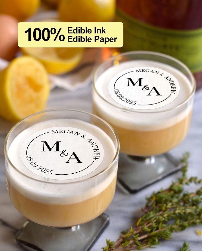 May include: Two clear glass cocktail glasses with a white edible paper topper that says "MEGAN & ANDREW" with the initials "M&A" and the date "08.09.2025".