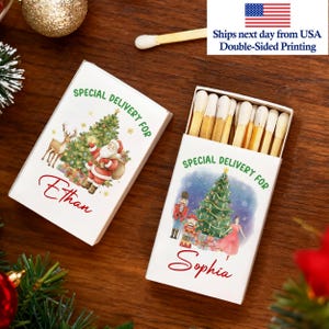 May include: Two white matchboxes with Christmas-themed illustrations. One box features Santa Claus and a reindeer, the other a ballerina and a nutcracker. Both boxes have the text "Special Delivery For" and a name.