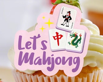 May include: A cupcake topped with a pink decoration that says "Let's Mahjong." The decoration features a joker card and two Mahjong tiles with a red character and a green dragon. Yellow stars are also included.