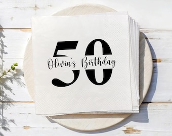 May include: A stack of white paper napkins with a black "50" and the text "Olivia's Birthday" in a script font. The napkins are on a wooden serving tray, perfect for a 50th birthday celebration.