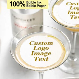 K&ouml;nnte beinhalten: Zwei Martinigl&auml;ser mit essbaren Papierkreisen, auf denen "Custom Logo Image Text" und "Custom Logo Image Text" steht. Das essbare Papier besteht aus 100% essbarer Tinte und essbarem Papier.