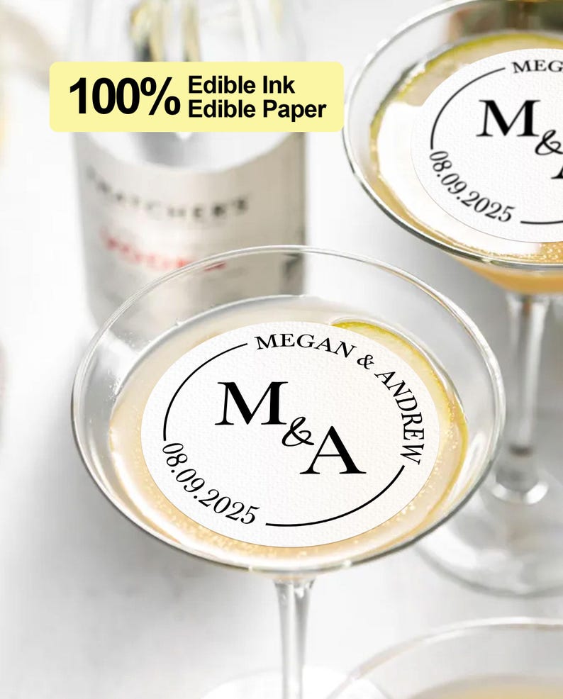May include: Two white round edible paper drink toppers with black text. The text reads "Megan & Andrew" and "M&A" with the date "08.09.2025".