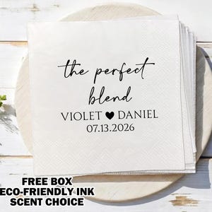 May include: A stack of white square napkins with the text "the perfect blend" in black script. Below the text are the names "VIOLET ♥ DANIEL" and the date "07.13.2026". The napkins are on a round, light-colored wooden plate.